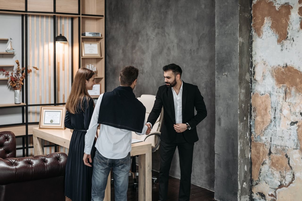 Business professionals discussing in a stylish, modern office setting with a handshake agreement.